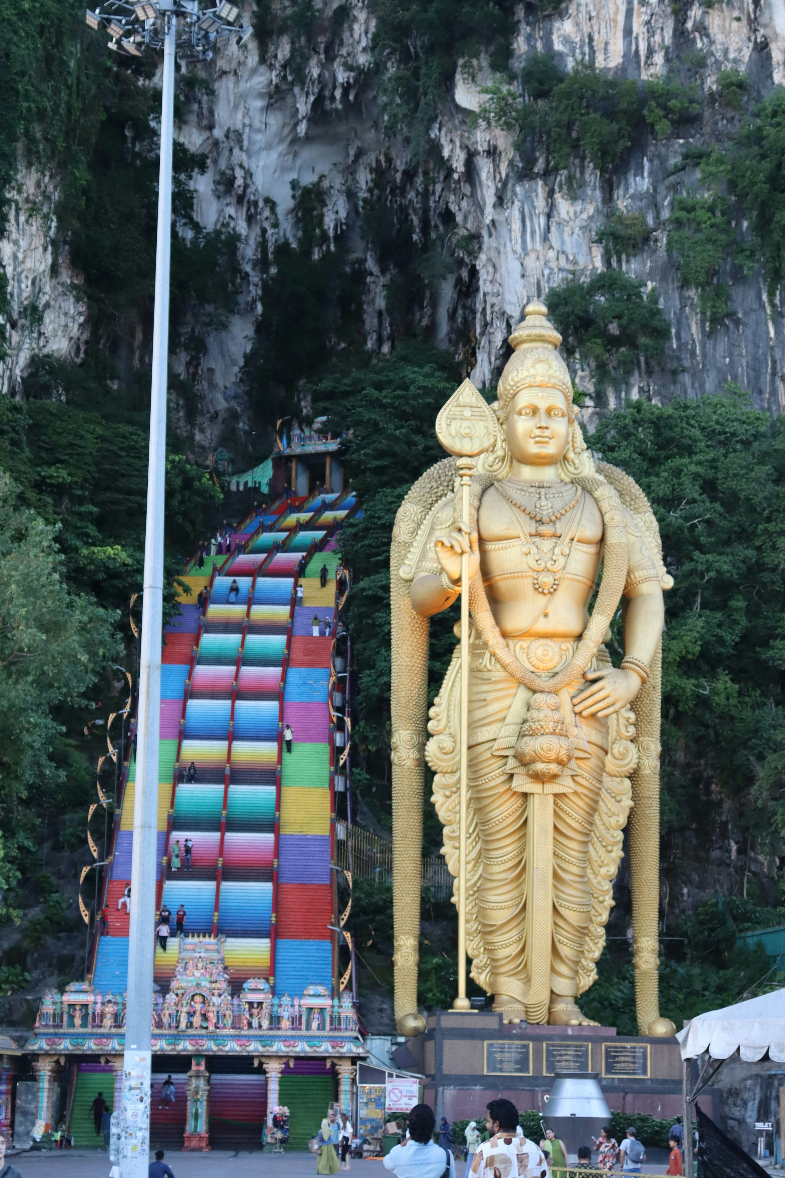 Colorful steps up to a cave with a giant gold statue of the Hindu god Murugan.