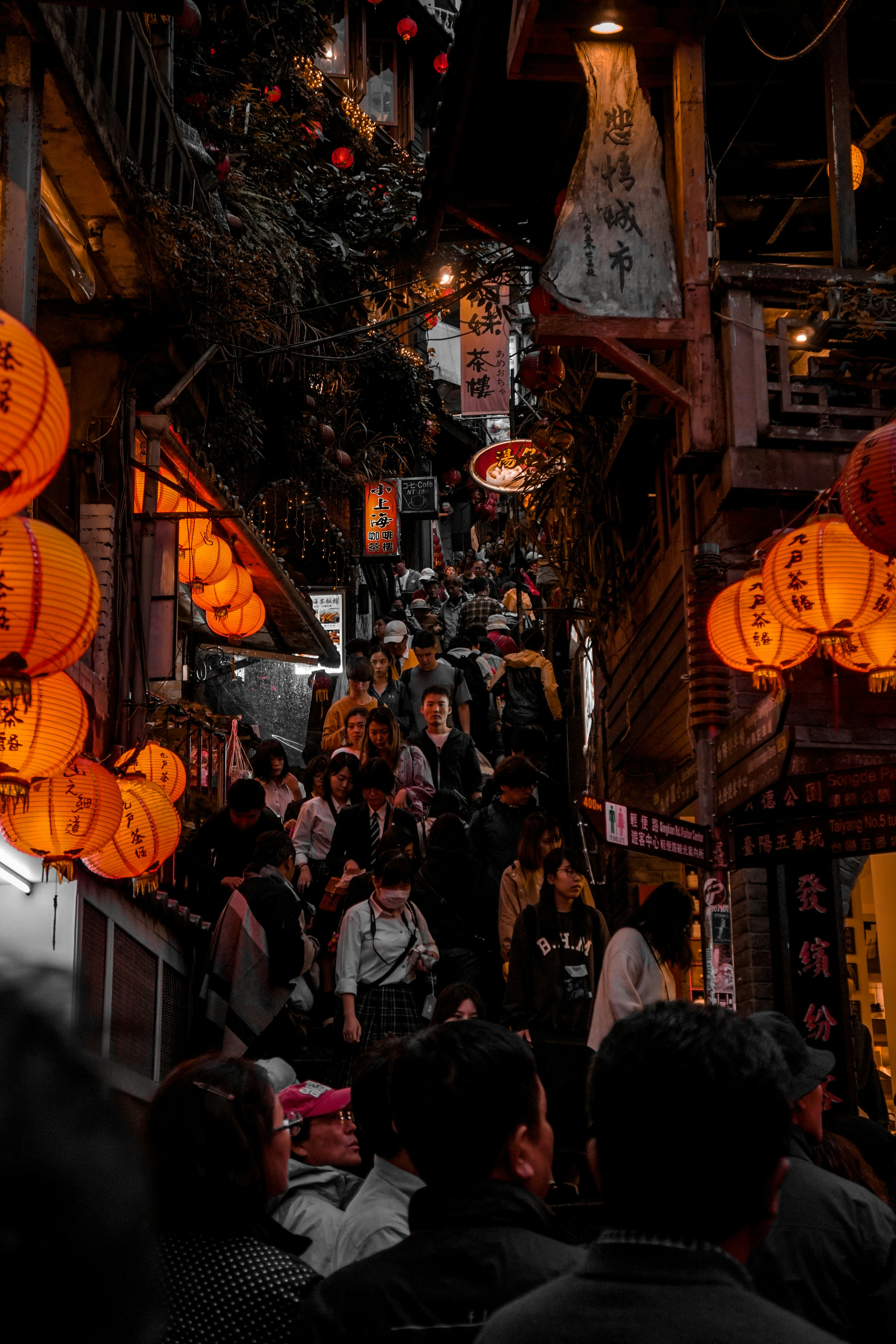 Red lantern lit stairway full of people at night.